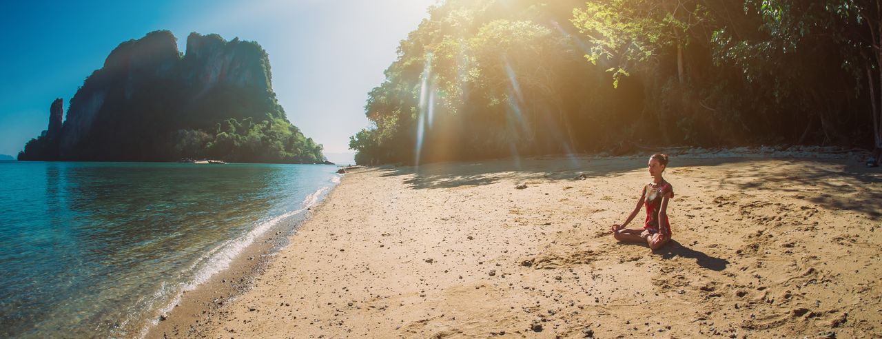 Eine Frau meditiert am Meer