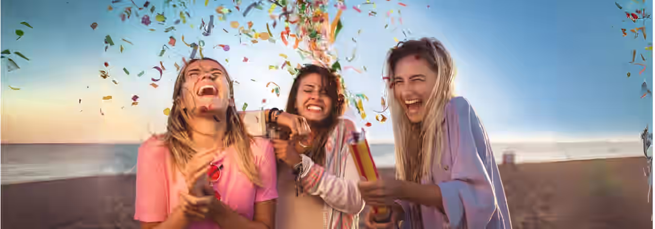 3 Freundinnen mit Konfettikanone am Strand