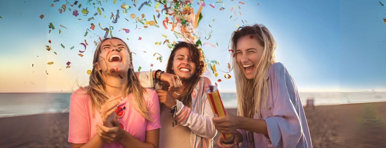 3 Freundinnen mit Konfettikanone am Strand