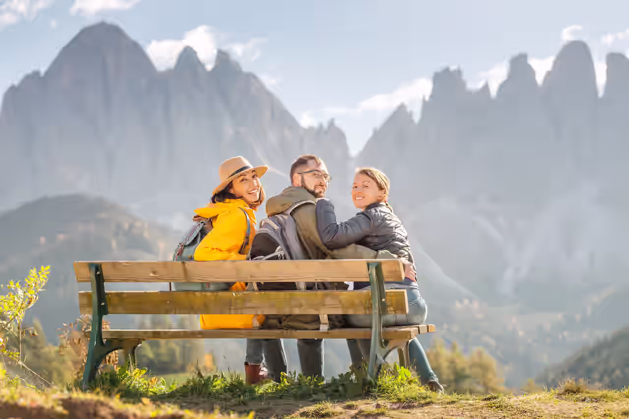 Eine Gruppe Wanderer auf einer Bank mit Panorama-Blick auf die Dolomiten