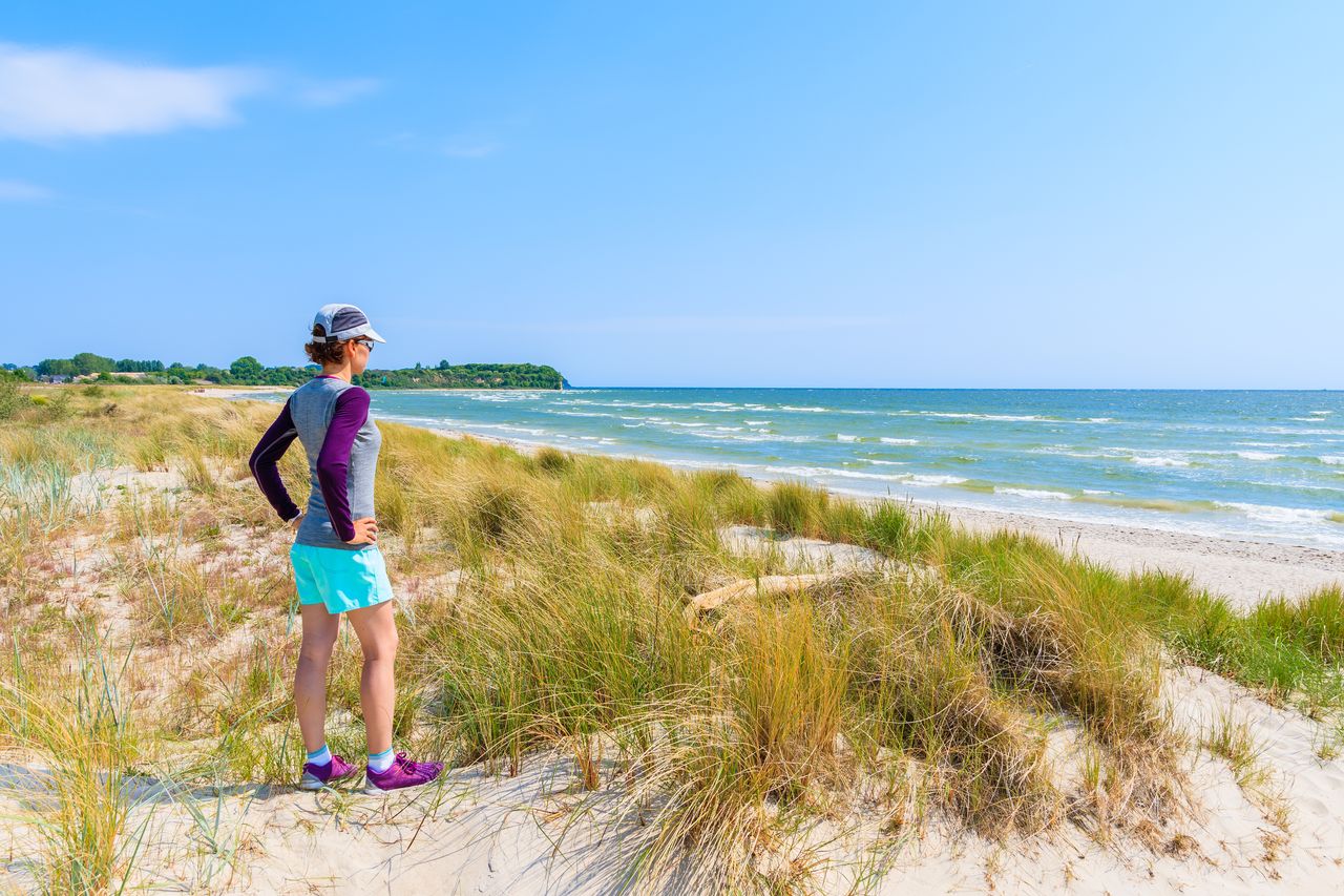 Sportlich gekleidete Frau am Strand der Ostsee in Mecklenburg-Vorpommern