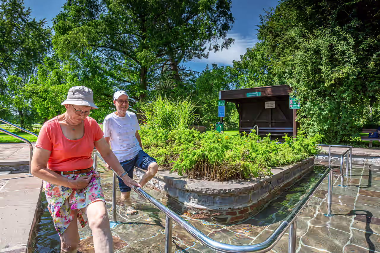 Ein älteres Paar schreitet durch ein Kneipptretbecken