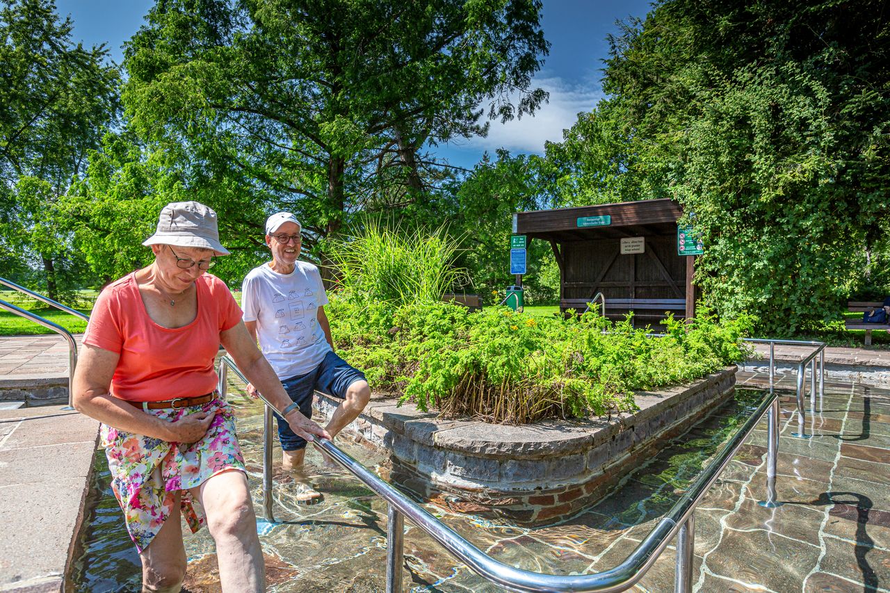 Ein älteres Paar schreitet durch ein Kneipptretbecken