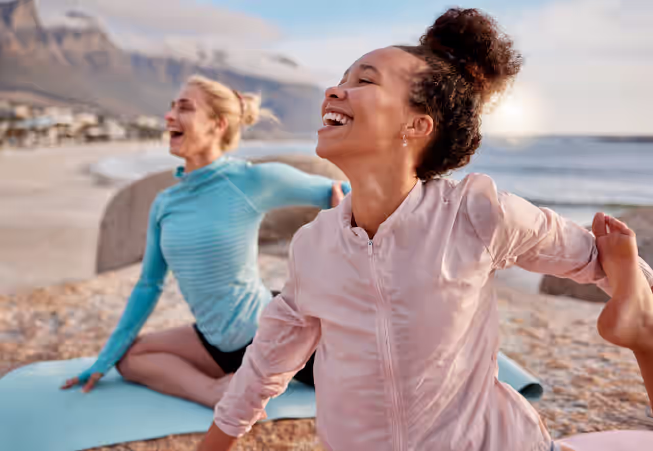 Zwei Frauen am Strand, die Yoga machen