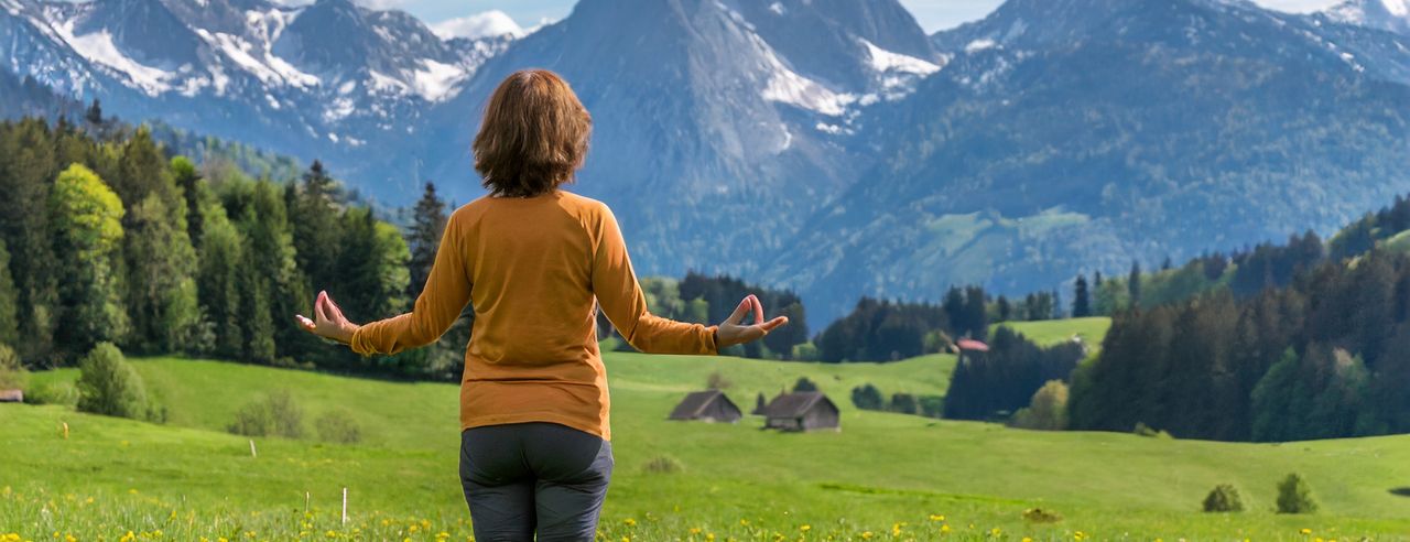 Eine Frau meditiert auf einer schönen Wiese in Oberstaufen in Ihrem Yoga Urlaub