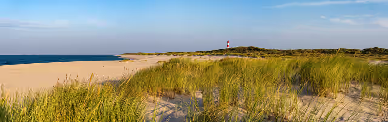 Blick auf einen Nordseestrand, im Hintergrund ein Leuchtturm