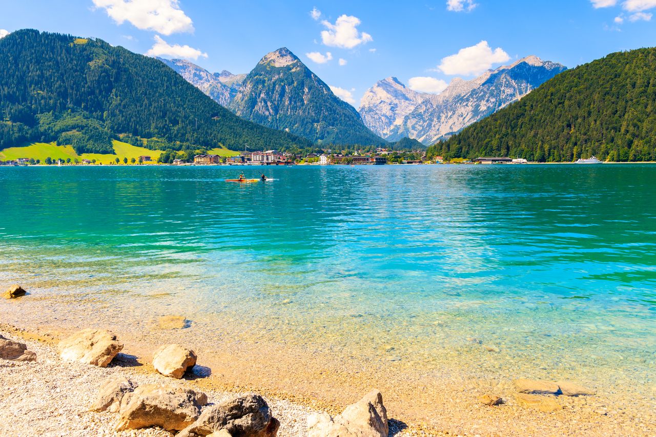 Tirol im Sommer: Klarer Bergsee mit Kanus und die alpine Landschaft