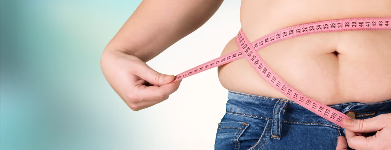 Eine Frau hält sich ein Maßband um den Bauch