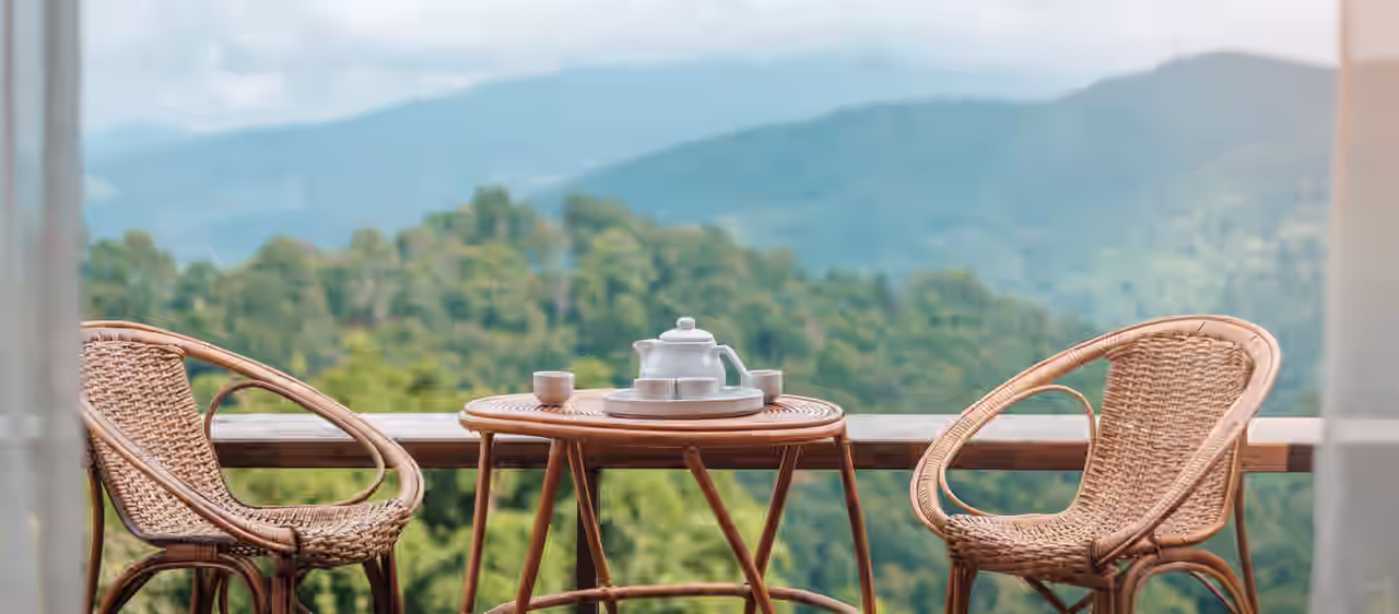 Kaffeetisch und Stühle, im Hintergrund grüne Hügel und Berge
