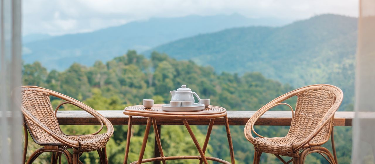 Kaffeetisch und Stühle, im Hintergrund grüne Hügel und Berge