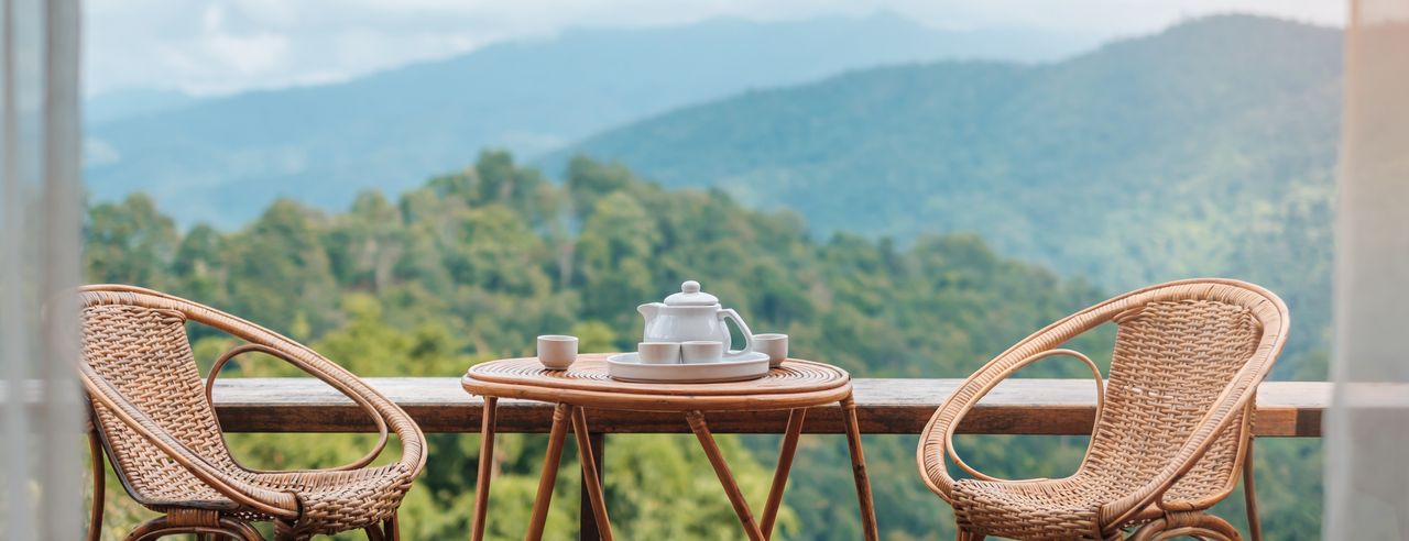 Kaffeetisch und Stühle, im Hintergrund grüne Hügel und Berge