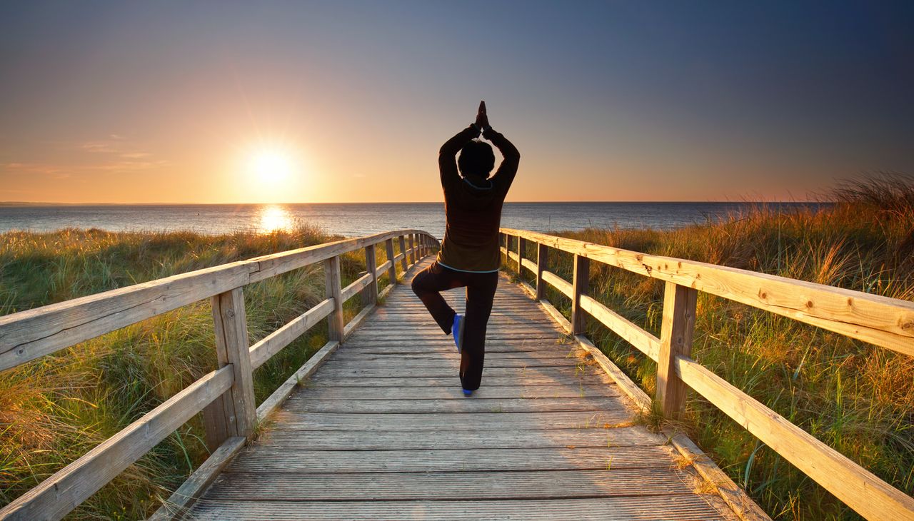 Eine Frau übt Yoga im Urlaub über das Wochenende in Mecklenburg-Vorpommern am Steg zum Strand
