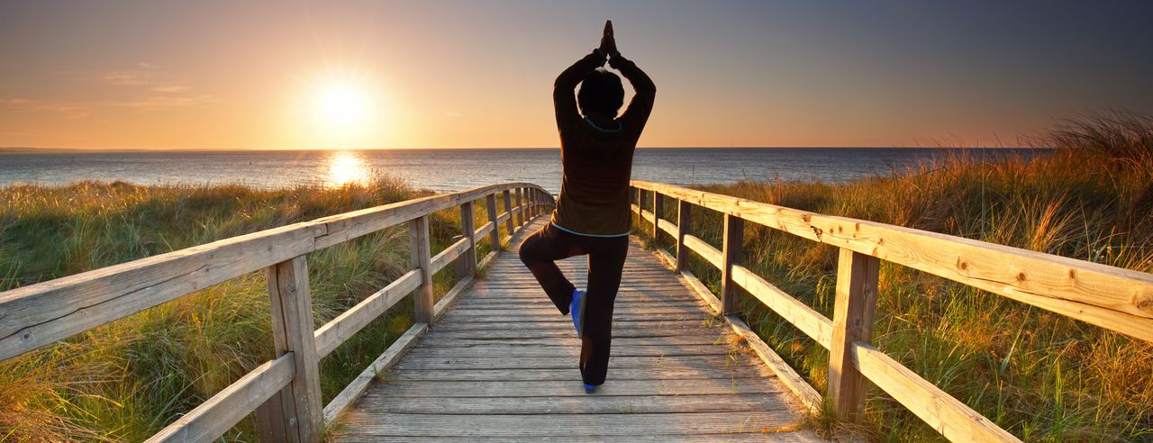 Eine Frau übt Yoga im Urlaub über das Wochenende in Mecklenburg-Vorpommern am Steg zum Strand