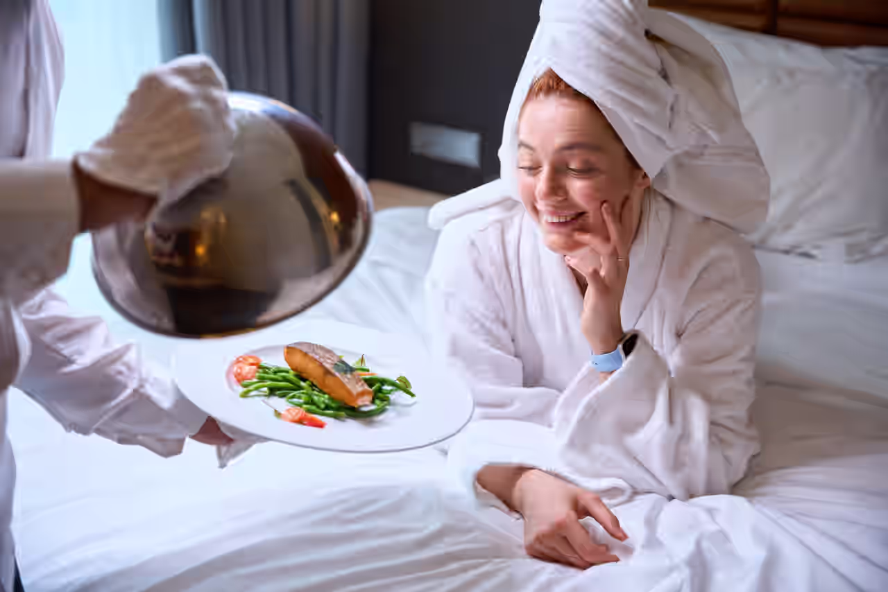 Eine Frau im Bademantel frühstückt im Hotelzimmer