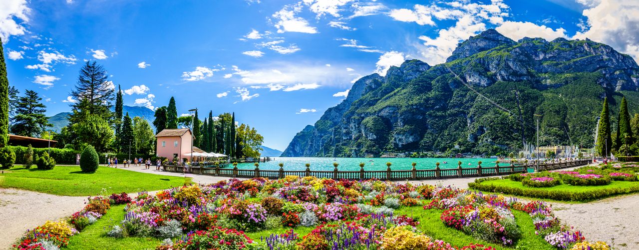 Blumenlandschaft im Vordergrund mit der Berglandschaft im Hintergrund und Blick auf den Gardasee beim Kurzurlaub genießen