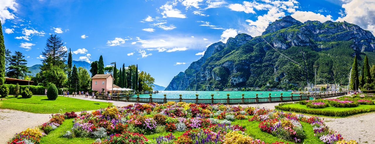 Blumenlandschaft im Vordergrund mit der Berglandschaft im Hintergrund und Blick auf den Gardasee beim Kurzurlaub genießen