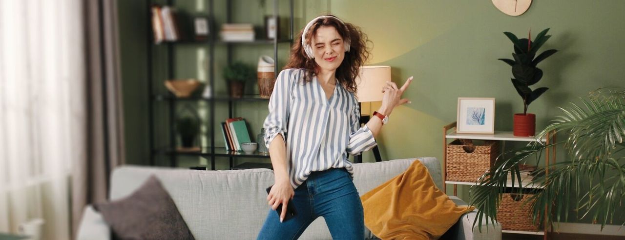 Frau tanzt mit Kopfhörern im Wohnzimmer