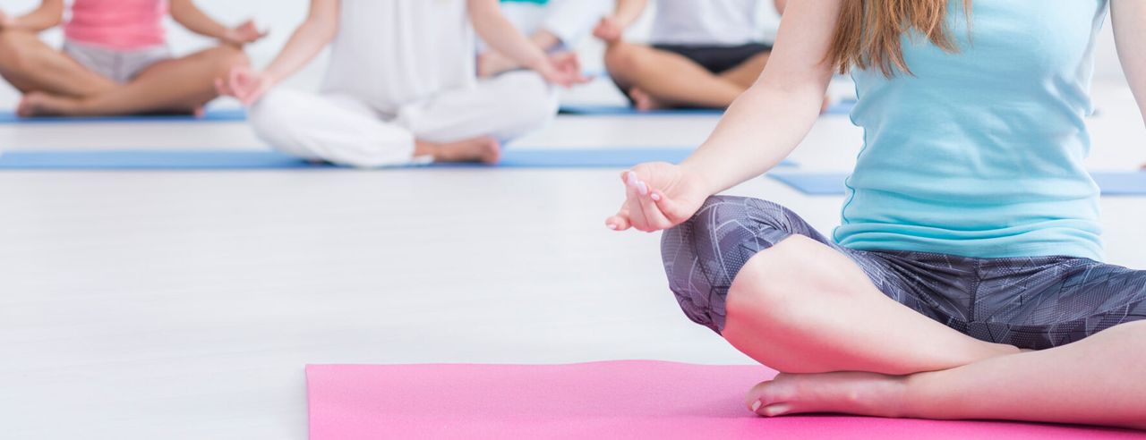 Mehrere Personen im Meditationssitz auf Yogamatten