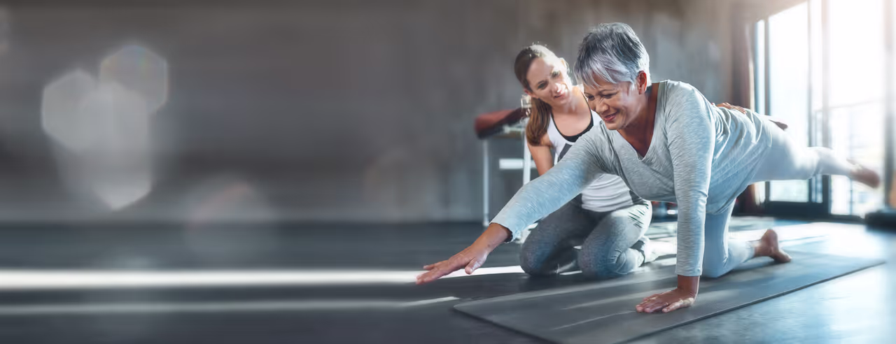 Due donne in posizione yoga davanti a uno sfondo rosa