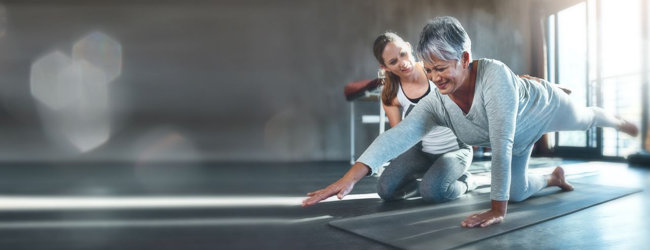 Zwei Frauen in Yoga Pose vor einem rosa Hintergrund