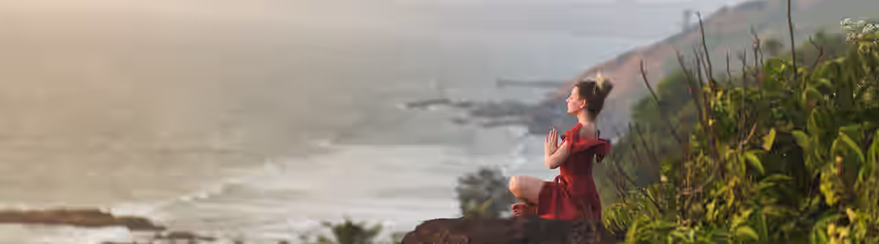 Eine Frau meditiert mit Blick aufs Meer