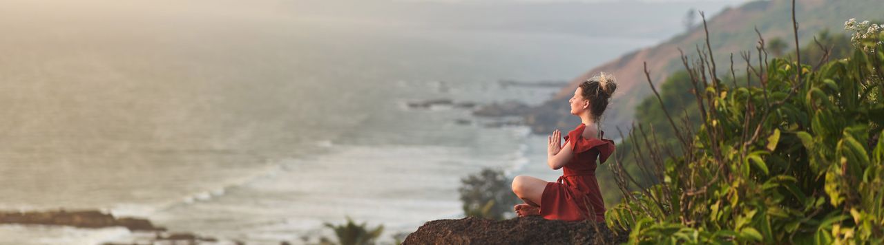 Eine Frau meditiert mit Blick aufs Meer