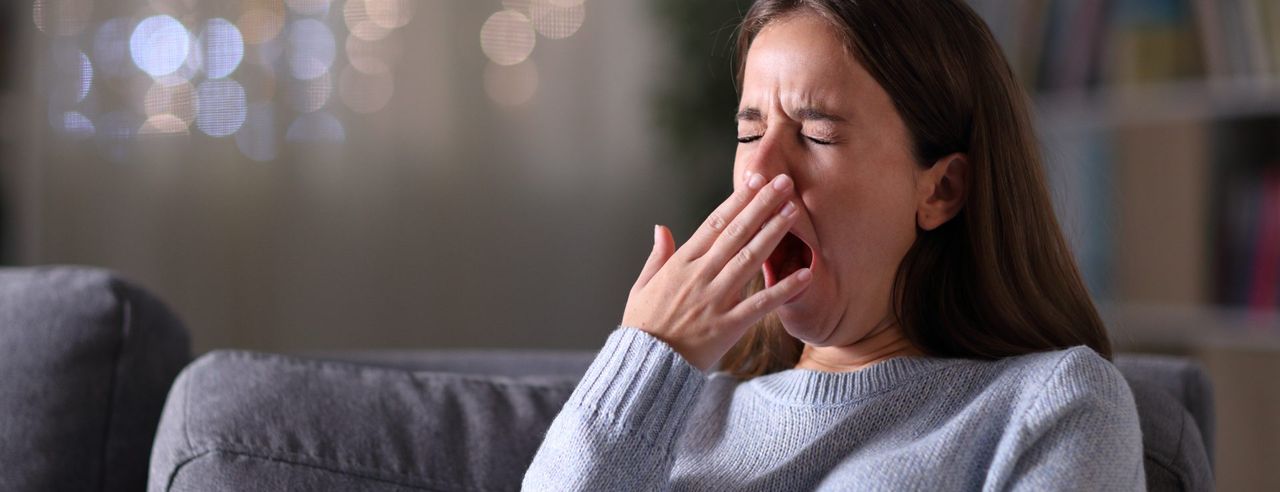 Frau hält sich gähnend die Hand vor den Mund