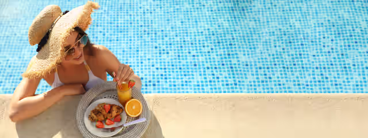 Eine Frau im Pool mit Essen und Getränk am Poolrand