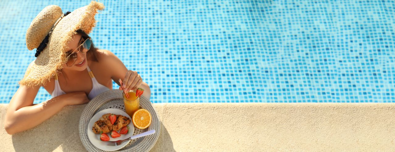 Eine Frau im Pool mit Essen und Getränk am Poolrand