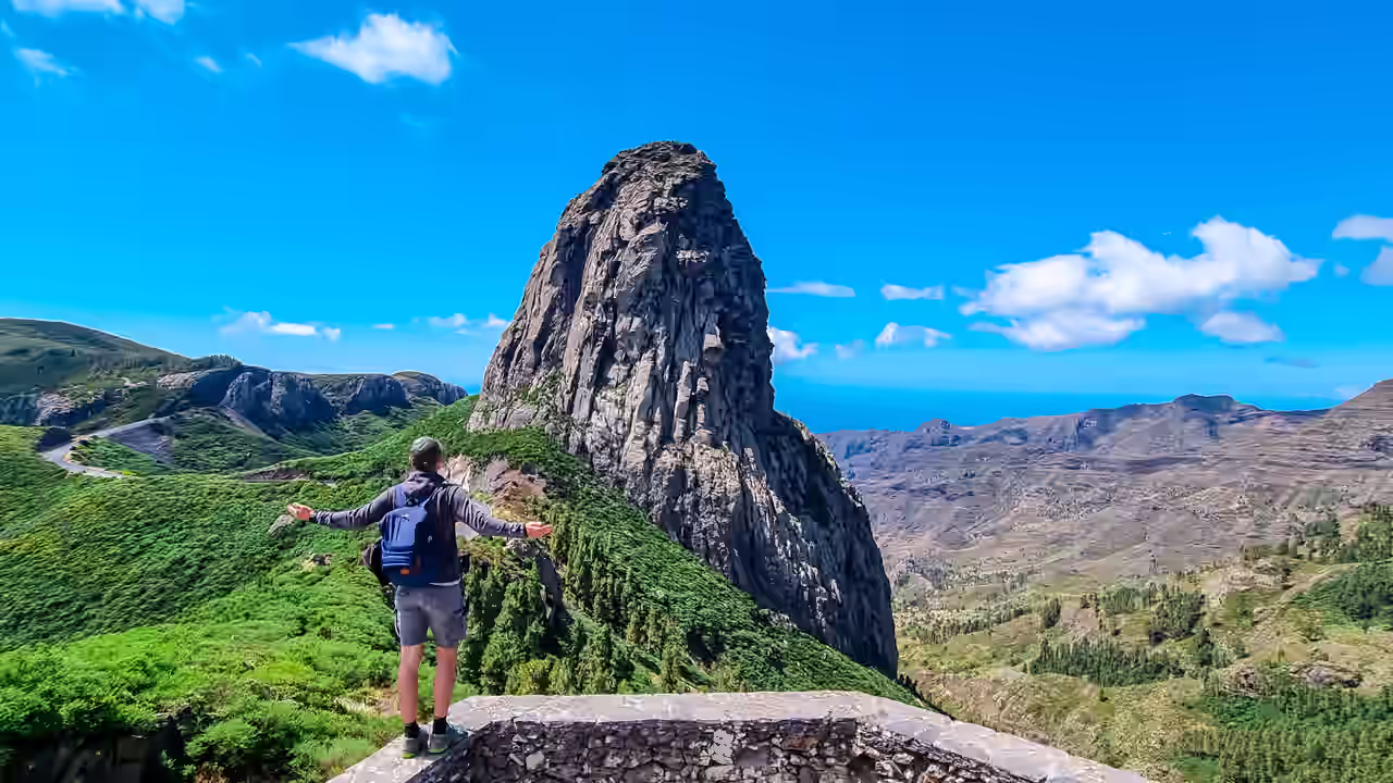 Sportlicher Mann mit Rucksack vor der massiven Vulkangesteinsformation Roque de Agando im Nationalpark Garajonay auf La Gomera