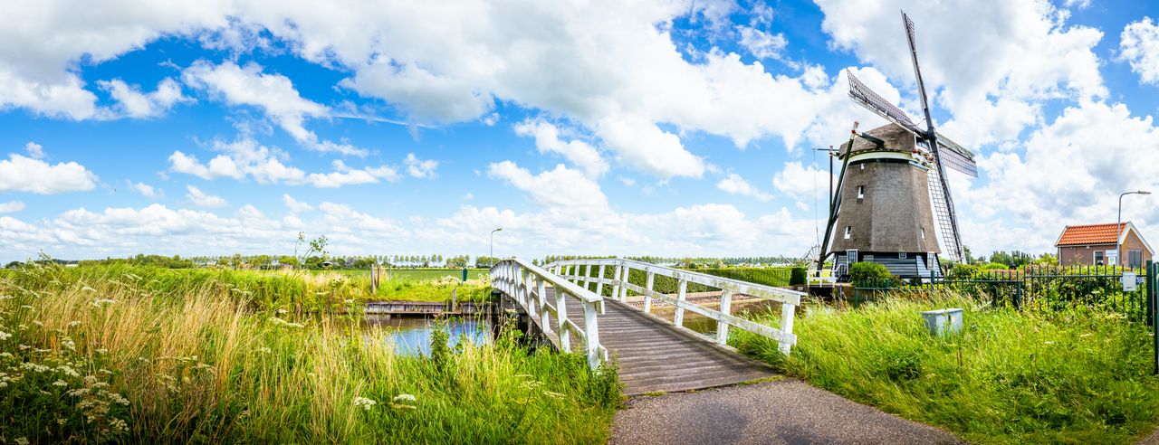 Eine Windmühle über einen Kanal in den Niederlanden bei einem Kurzurlaub entdecken