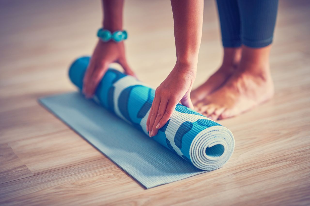 Eine Frau rollte eine blaue Yoga Matte aus