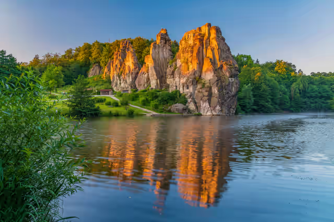 Felsformation Externsteine an einem See im Teutoburger Wald bei aufgehender Sonne